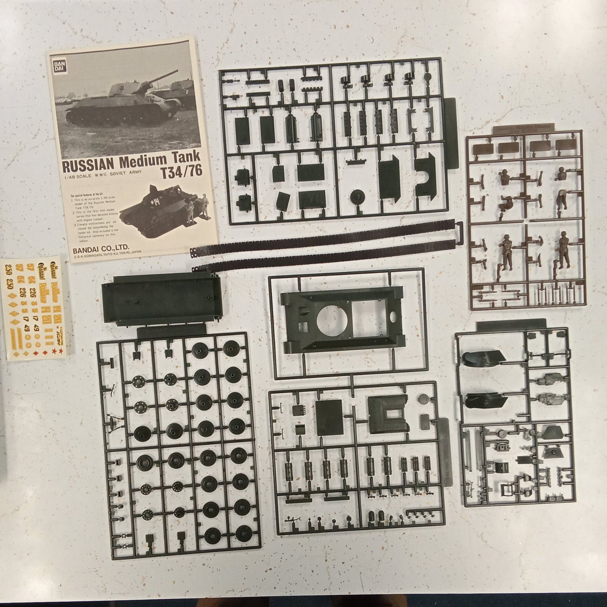Model kit packaging with various parts and a small image of a tank on a white background.